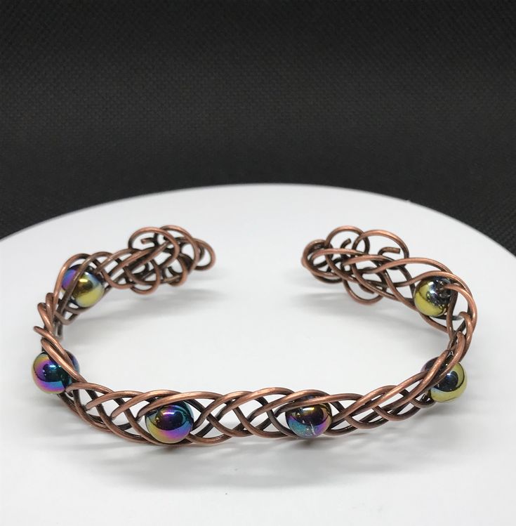 18 gauge copper braided together with rainbow glass beads in this 7" cuff bracelet. Adjustable. This bracelet has been antiqued, polished and sealed to prevent tarnishing. Sealed with Protectaclear. ProtectaClear is a clear, protective coating that is tough enough to protect jewelry and is safe for wear against skin. ProtectaClear is practically invisible once applied and will seal and protect jewelry from tarnish, oxidation, and corrosion Adjustable Iridescent Bangle Bracelet, Adjustable Iridescent Bangle Jewelry, Iridescent Adjustable Bangle Bracelet, Iridescent Adjustable Bangle Jewelry, Beaded Bronze Copper Bracelets, Bronze Beaded Copper Bracelets, Adjustable Beaded Copper Bracelets, Glass Beads Bracelet, Rainbow Glass