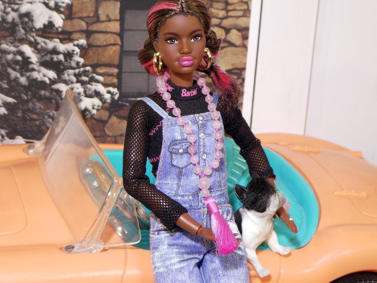 a barbie doll holding a dog in front of a car