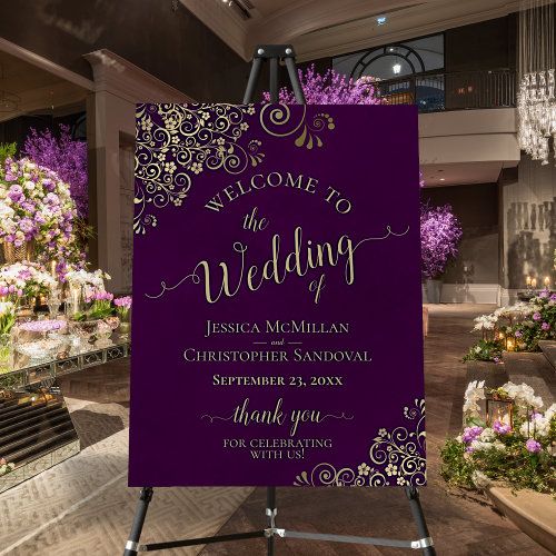 a purple wedding sign in the middle of a room with flowers and chandeliers