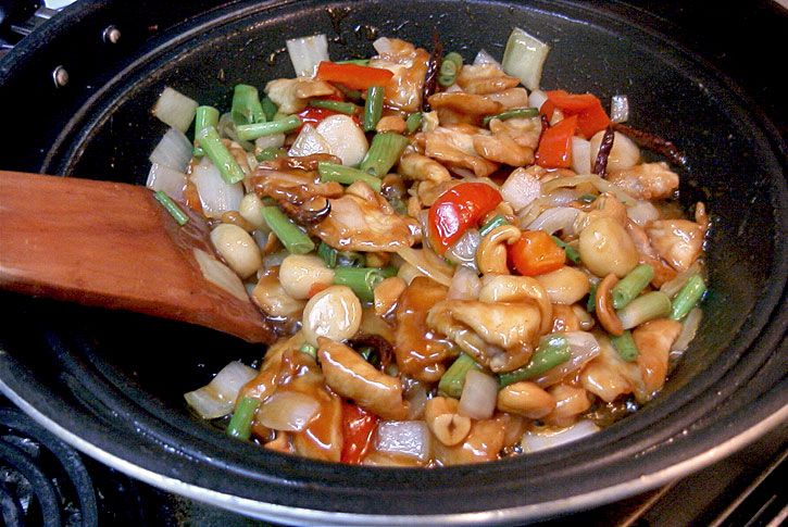 the food is being cooked in the skillet on the stove with a wooden spoon