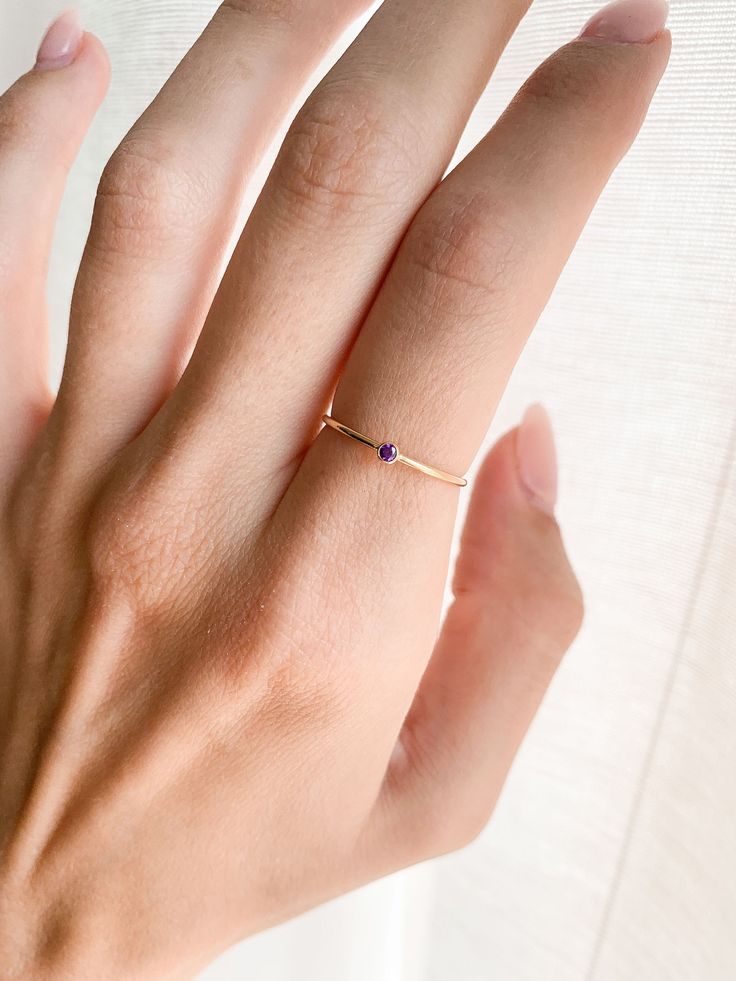 Our February Ring is the perfect gift for anniversary, wedding, bridal proposal, birthday or for a new mama to be! They are great stacking rings as well and look great with any of our other stacking rings. DETAILS: - February birthstone - 14k Gold Fill, 1mm band - Purple CZ stone, 2mm 14K GOLD FILL: Gold fill is a pressure bonded material that has 100% more gold than gold plating. It does not chip, flake or rub off and is tarnish resistant. Anyone who can wear gold can wear gold filled without w Elegant Personalized Crystal Ring As Gift, Simple Design Crystal Ring For Anniversary, Dainty Personalized Diamond Promise Ring, Elegant Adjustable Birthstone Ring For Gift, Dainty Promise Jewelry With Simple Design, Dainty Jewelry For Promise With Simple Design, Dainty Crystal Ring With Simple Design For Anniversary, Personalized Dainty Diamond Ring For Wedding, Simple Design Open Ring Birthstone For Anniversary