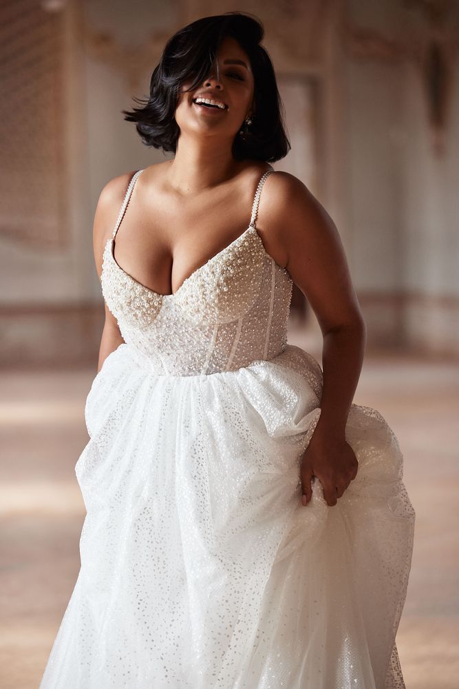 a woman in a white dress smiling and posing for the camera with her hands on her hips