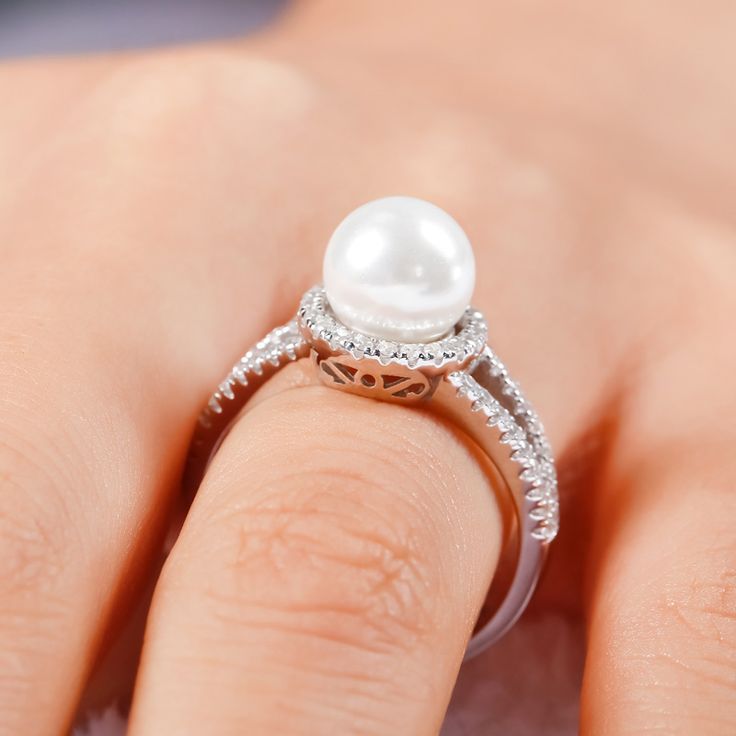 Pearl-the queen of gems and the gem of queens. Treat yourself with this elegant ring. Crafted in sterling silver, the ring features a 8mm faux pearl set in a glistening halo of round stones and its classic split shank. The elegant and timeless look won't be out of date in along time. This ring will be a nice holiday gift for Mom, sister,friend or yourself! Treat yourself or surprised her with this dainty piece. It won't disappoint you!Carat Weight: 4.2 ctStone Size: 8 mmStone Type: Jeulia® StoneNumber of Stones: 1 Stone Color: Diamond WhiteStone Shape: RoundCarat Weight: 0.58 ctStone Size: 1.1 mmStone Type: Jeulia® StoneNumber of Stones: 58 Stone Color: Diamond WhiteStone Shape: RoundWeight: 4.3 gWidth: 2.42 mmHeight: 8 mmThickness: 1.27 mmMaterial: 925 SilverPlating Color: Silver Pearl Ring With Diamond Accents, Silver Pearl Rings With Diamond Accents, Silver Rings With Diamond Accents And Pearl, Elegant Diamond Pearl Ring For Promise, Elegant Diamond Pearl Promise Ring, Elegant Pearl Ring With Diamond Center Stone, Fine Jewelry Diamond White Pearl Rings, Elegant Pearl Rings In Diamond White, Elegant Diamond White Pearl Rings