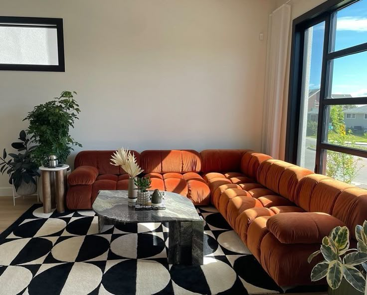 a living room with an orange couch and black and white rugs on the floor