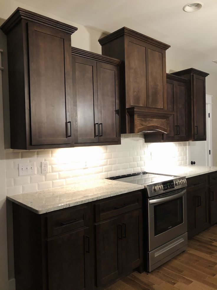 an empty kitchen with dark wood cabinets and white counter tops is seen in this image