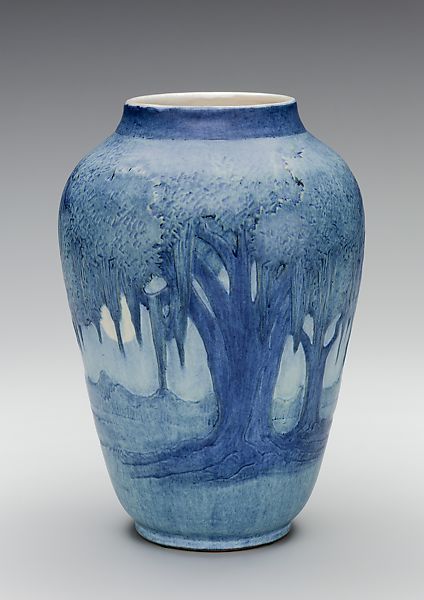 a blue and white vase with trees painted on it