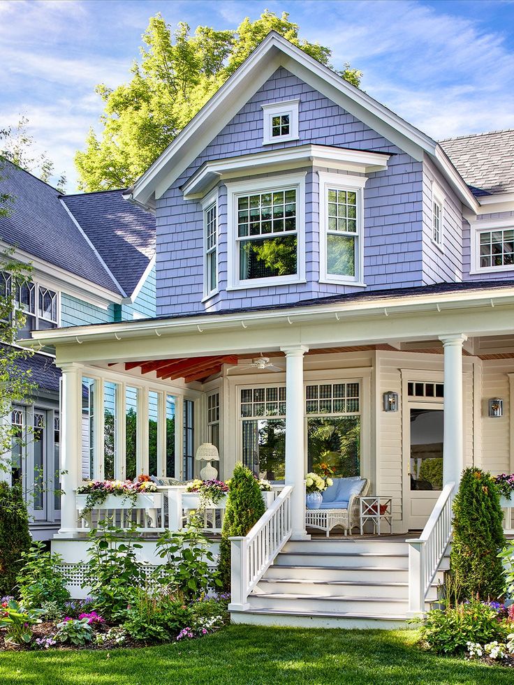 a house with white trim and blue sidings on the front porch, covered in flowers