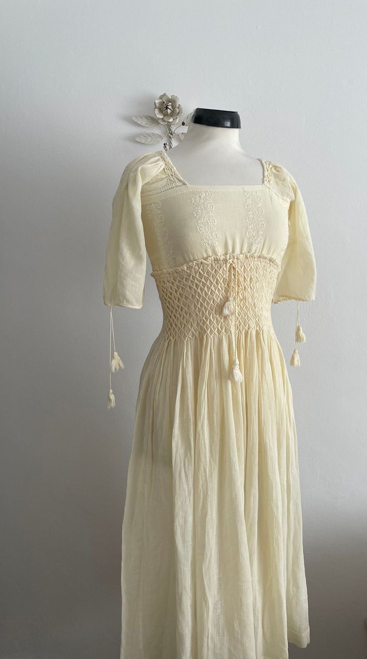 Vintage 1930s sheer buttercream cotton gauze dress with white embroidery, short sleeves,square neckline  and very wide smocked waist. Fits like: xs/small Bust:  34" Waist: 28-30" Hip: free Length: 46" [i n f o] Era: 1930s Brand/maker: n/a Fabric content: cotton Condition: excellent Fitted Bohemian Smocked Dress With Short Sleeves, Vintage Smocked Summer Dress, Vintage Smocked Bodice Summer Dress, Fitted Vintage Smocked Dress For Summer, Fitted Bohemian Smocked Dress With Square Neck, Bohemian Prairie Dress With Square Neck For Summer, Fitted Cream Prairie Dress For Summer, Bohemian Summer Prairie Dress With Short Sleeves, Fitted Short Sleeve Bohemian Peasant Dress