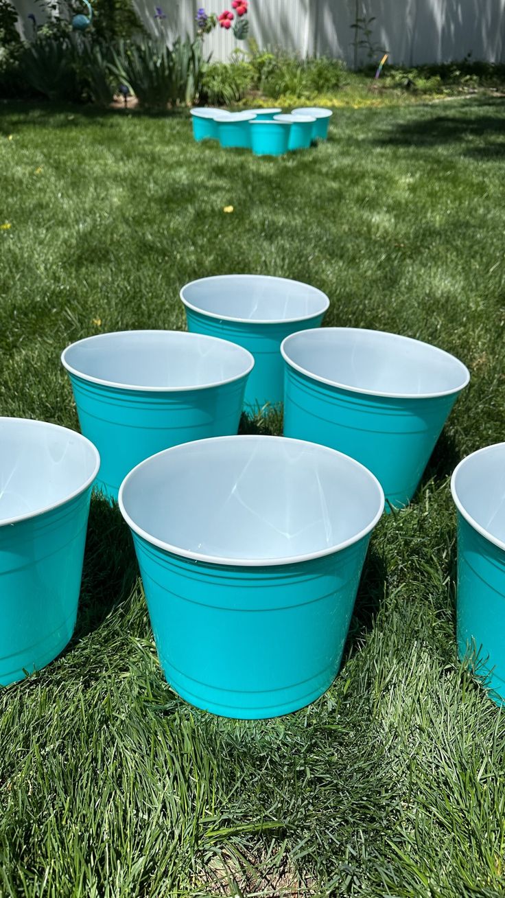 blue plastic buckets sitting in the grass