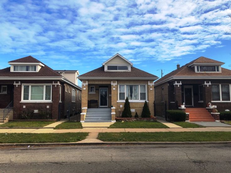 two houses on a street with grass and bushes