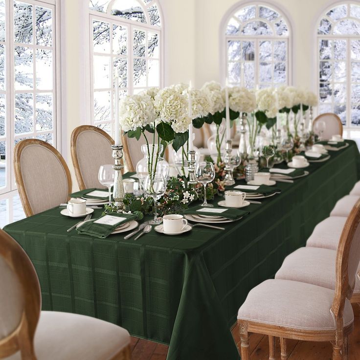 a long table is set with white flowers and place settings for an elegant dinner party