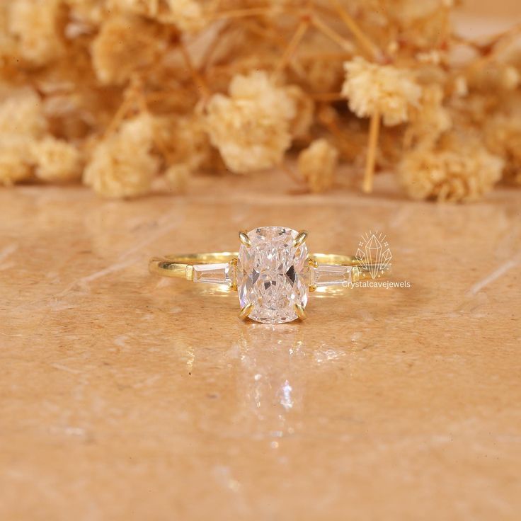 a diamond ring sitting on top of a table next to dried flowers and twigs in the background