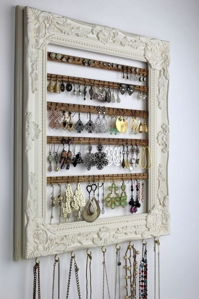 a wall mounted jewelry rack with several pairs of earrings hanging from it's sides