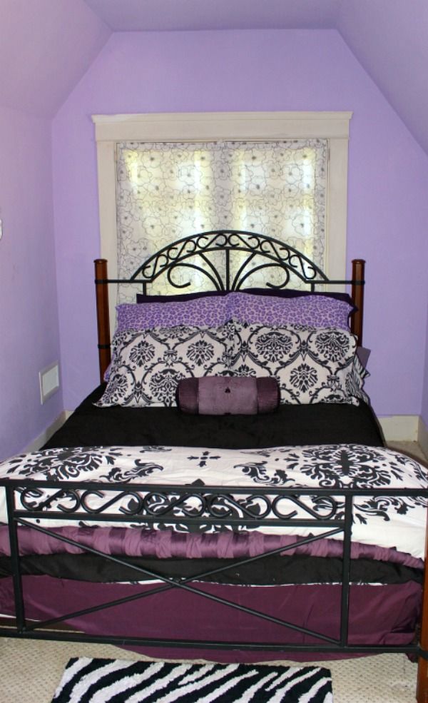 a bedroom with purple walls and black and white bedding