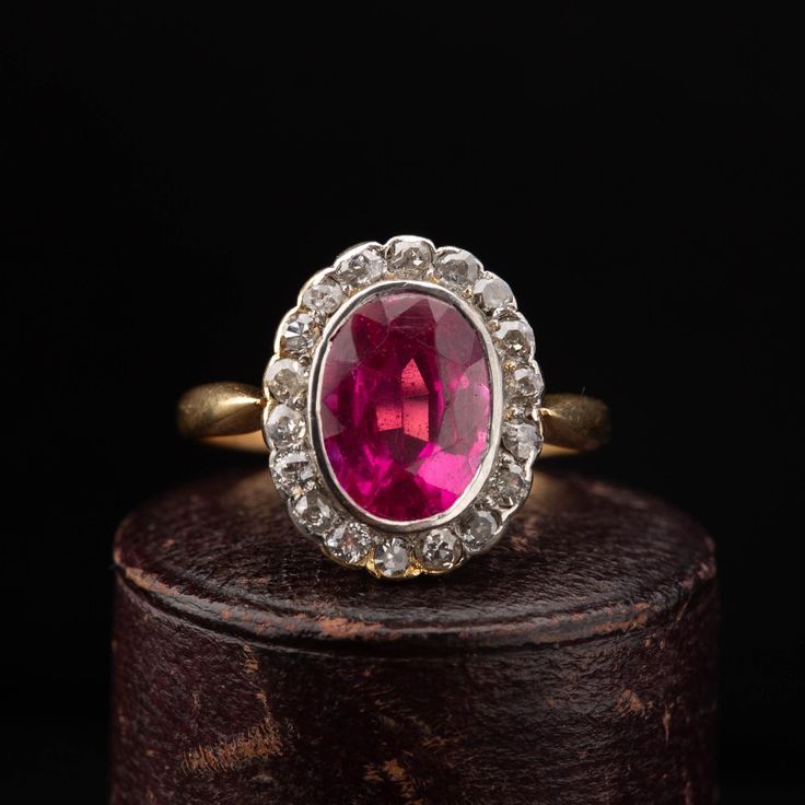 A beautiful Victorian oval cluster ring dating circa 1900, handcrafted in 18k yellow gold with a Platinum top, featuring a synthetic Ruby surrounded by 18 old cut diamonds weighing combined approx. 0.90 carat. The shoulders narrow as they meet the cluster giving a slim and elegant look to the ring. Period: Vitorian 1900s. Condition: Good condition commensurate to age. Material: 18k yellow gold, weighing 3.6 grams, acid tested. Gemstone: Oval synthetic Ruby measuring 9mm x 7mm, set in Platinum. D Victorian Ruby Ring, Antique Diamond Ring, Ruby Diamond Ring, Ruby Diamond Rings, Antique Diamond Rings, Ring Antique, Antique Diamond, Ruby Diamond, Cluster Ring