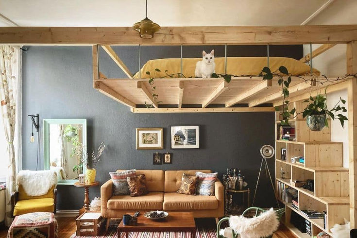 a living room filled with furniture and a cat sitting on top of the couches