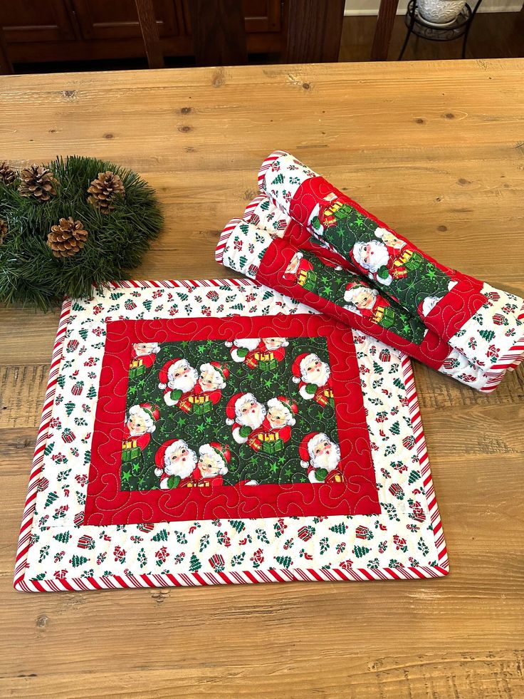 two quilted placemats sitting on top of a wooden table