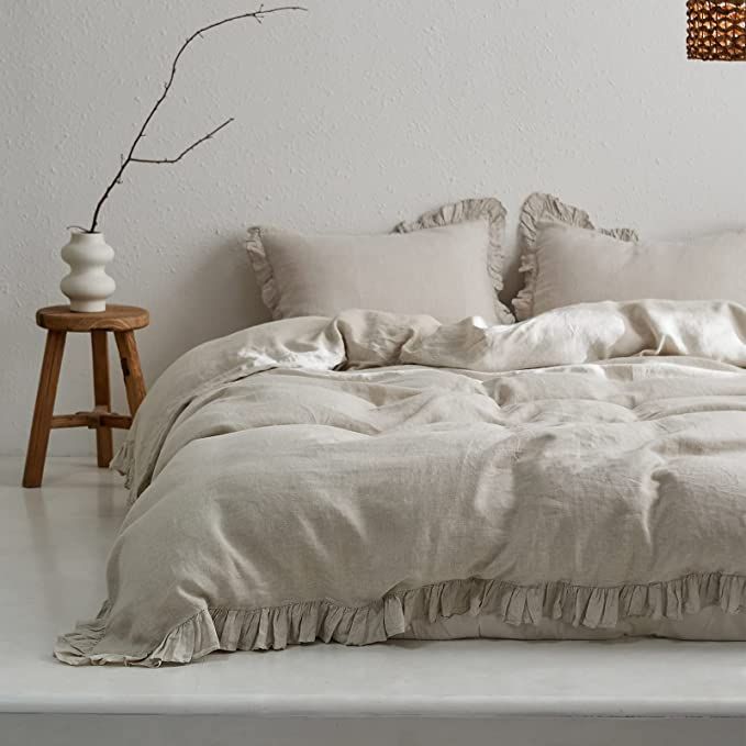 an unmade bed with white linens and ruffled pillows in a minimalist bedroom