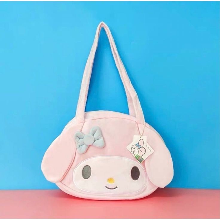 a pink purse with a bow on the side and a blue wall in the background