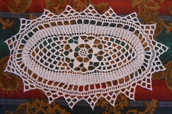 a white doily on top of a colorful table cloth