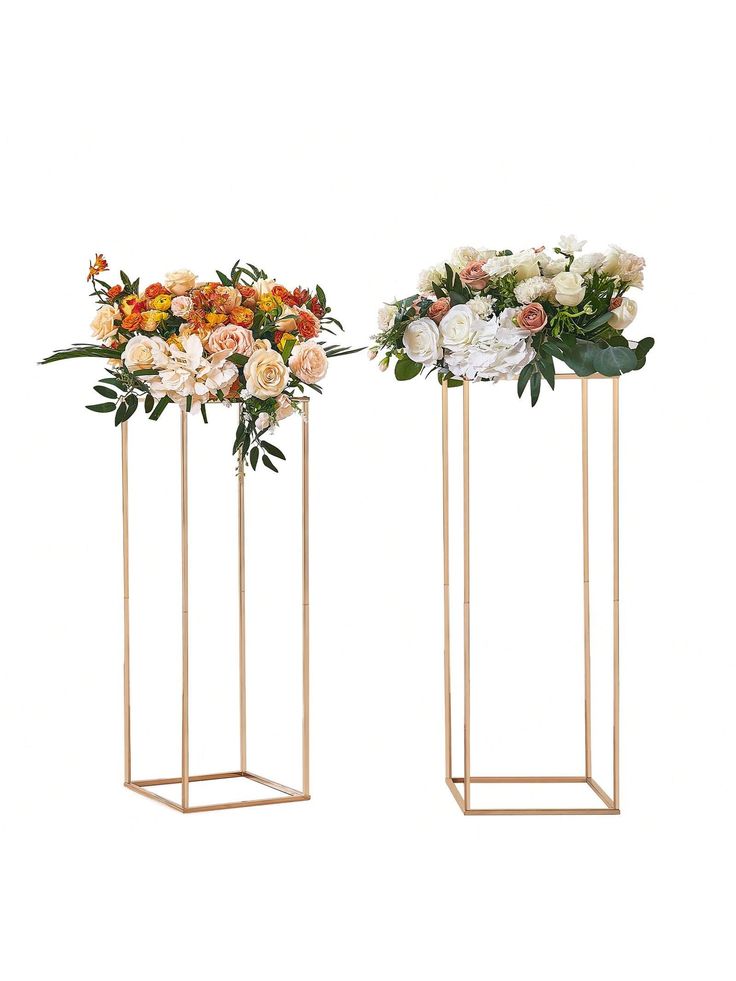 two gold vases with flowers in them are standing upright on stands against a white background