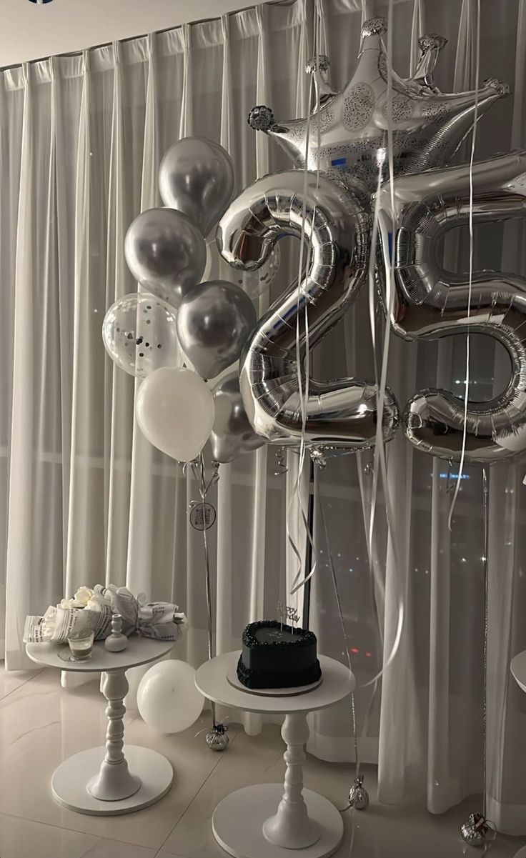 silver balloons are in the shape of an number and some other items sit on pedestals