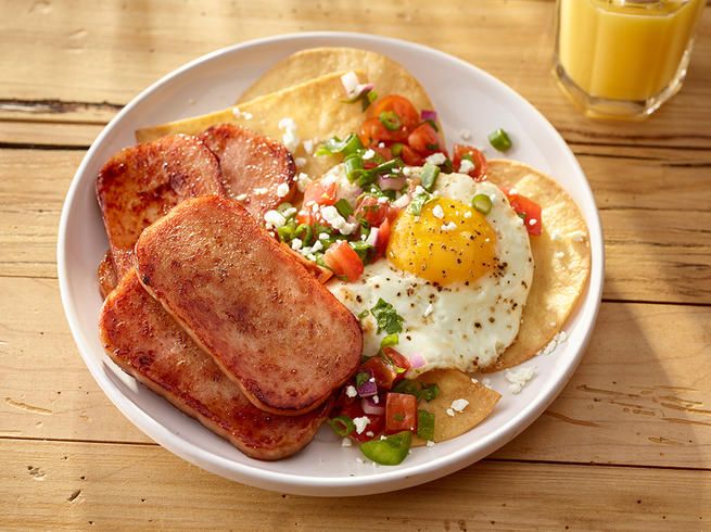 a white plate topped with breakfast foods on top of a wooden table