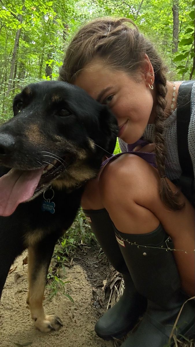 a girl is hugging her dog in the woods