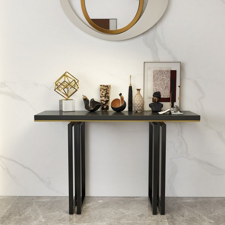 a console table with art on it in front of a circular mirror and wall decoration