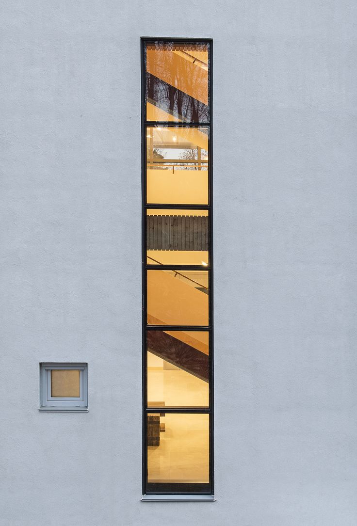 a white building with windows reflecting in it's side wall and another window on the other side