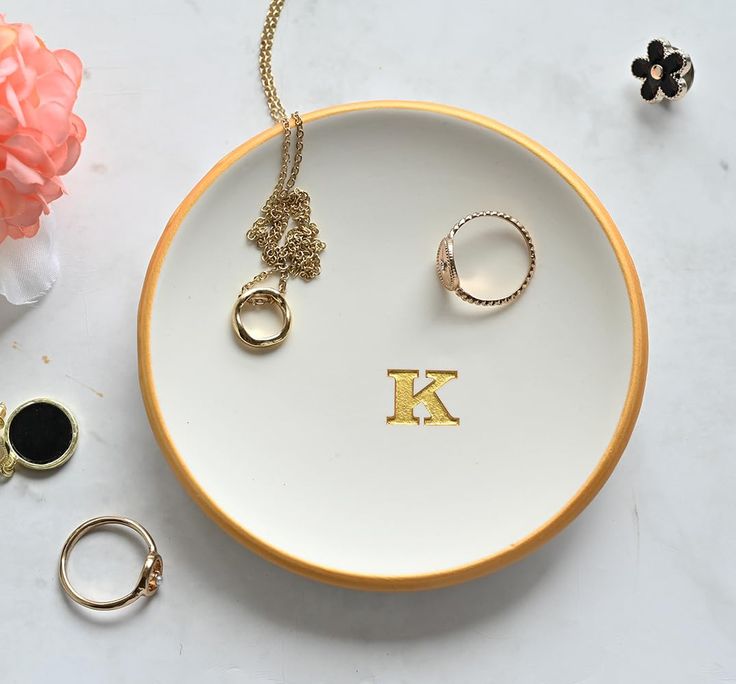 a plate with two rings on it next to some other jewelry and a flower vase