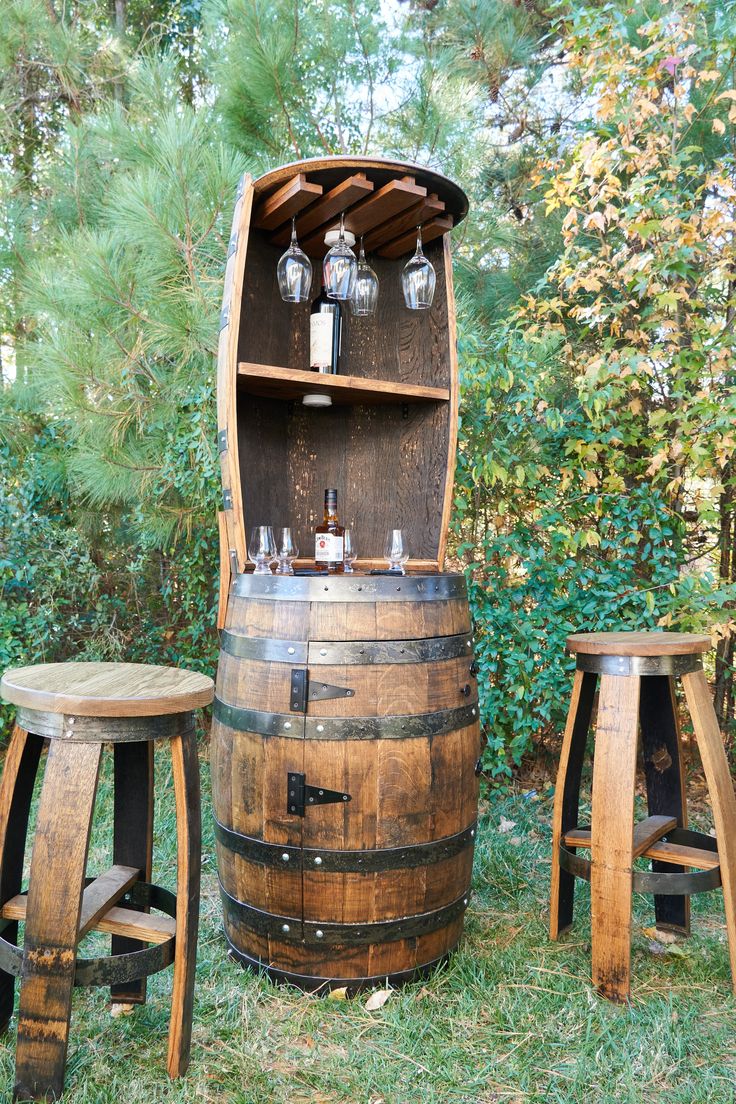 an old wooden barrel with two stools next to it and some bottles on top