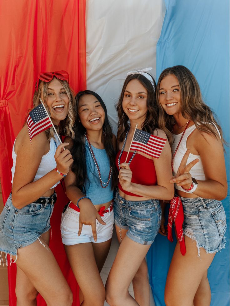 four girls are posing for the camera in front of an american flag