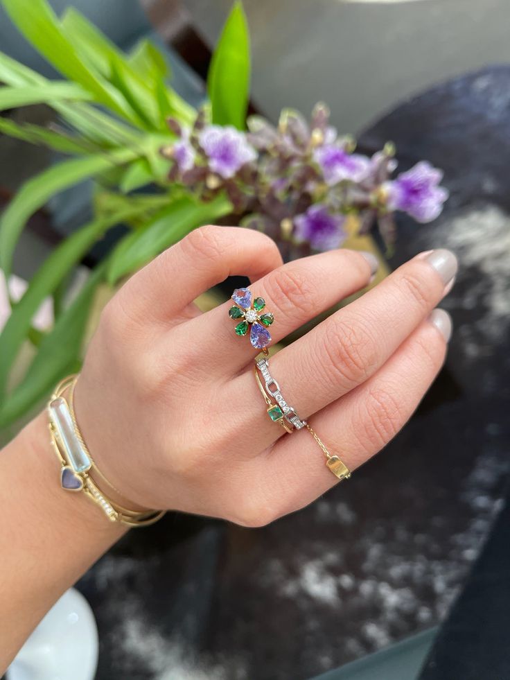 Our flora ring is as bright and vibrant as spring. Some of the rarest of all gems make up this gorgeous creation. Hand-selected tanzanites and tsavorites make this an unforgettable pairing.  The center of this ring is a beautiful vs quality diamond set to perfection in this handmade ring. Each “petal” of this ring is u Diamond Multi-stone Emerald Ring For May Birthstone, Green Multi-stone Sapphire Diamond Ring, Fine Jewelry Flower Ring With Accent Stones, Fine Jewelry Floral Rings With Accent Stones, Fine Jewelry Green Sapphire Multi-stone Ring, Fine Jewelry Green Multi-stone Sapphire Ring, Fine Jewelry Flower-shaped Multi-stone Rings, Green Multi-stone Diamond Ring, Fine Jewelry Sapphire Ring For May Birthstone