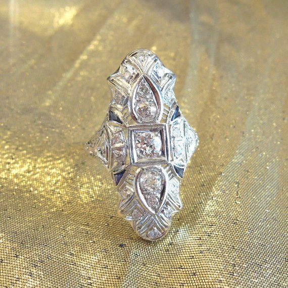 Almost a carat of diamonds (.90ct) embellish this filigreed platinum ring. In the center, a .35ct H-I color, VS clarity Old European Cut diamond dazzles. Surrounded by 21 smaller diamonds, weighing a combined .55ct., these vertically aligned rings are becoming increasingly difficult to find.Would make an ideal unusual engagement ring, or perfect anniversary or birthday gift for the woman who appreciates fine vintage jewelry.TOP MEASUREMENTS: 30mm X 18mm SIZE 7.5 (can be sized) Pear-shaped Single Cut Diamond Ring In Diamond White, Platinum Diamond Ring Baguette Cut In Silver, Art Deco Platinum Diamond Ring With Vvs Clarity, Pear-shaped White Gold Diamond Ring With Single Cut, Heirloom Pear-shaped Diamond Cut Ring, Art Deco Platinum Diamond Ring In Diamond White, Classic Pear-shaped Diamond Ring With Rose Cut Diamonds, Dazzling Formal Rose Cut Diamond Ring, Silver Pear-shaped Diamond Ring With Single Cut