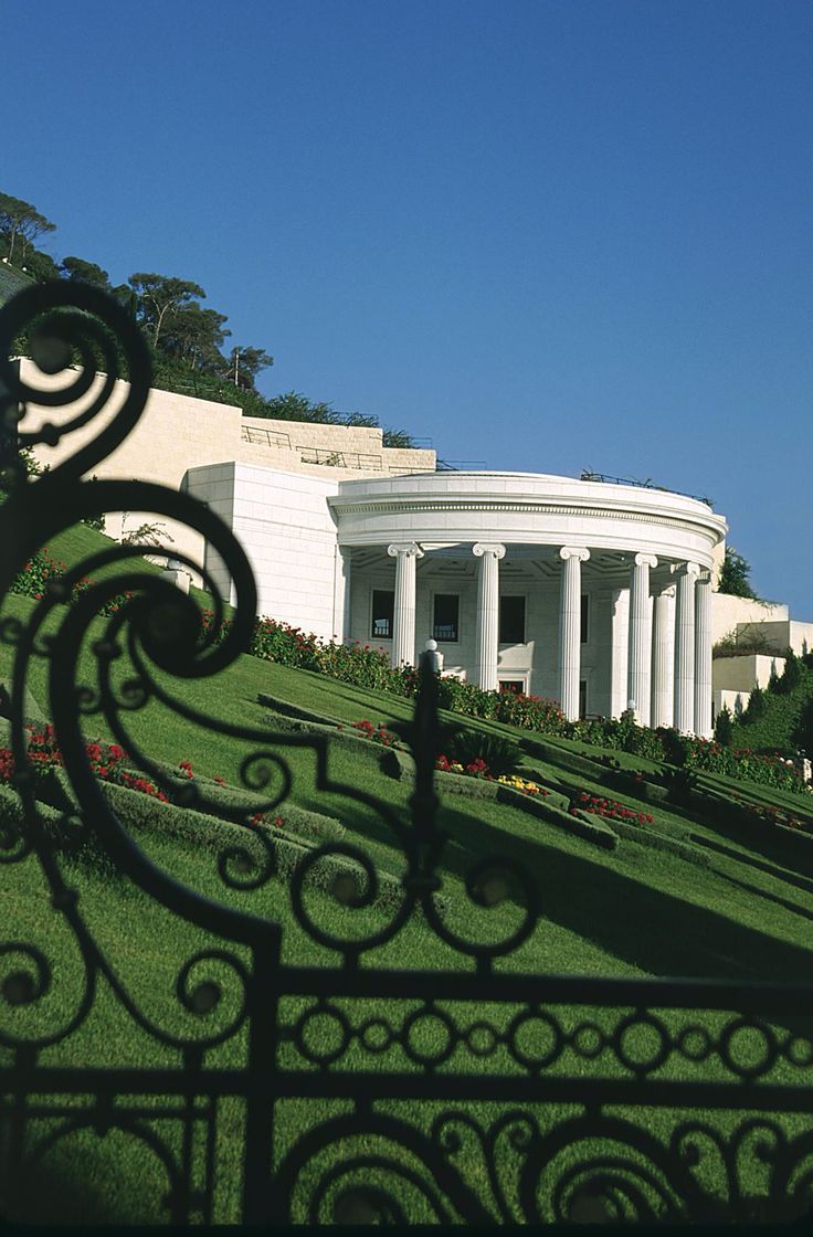 the white building has columns on it's sides and is surrounded by greenery