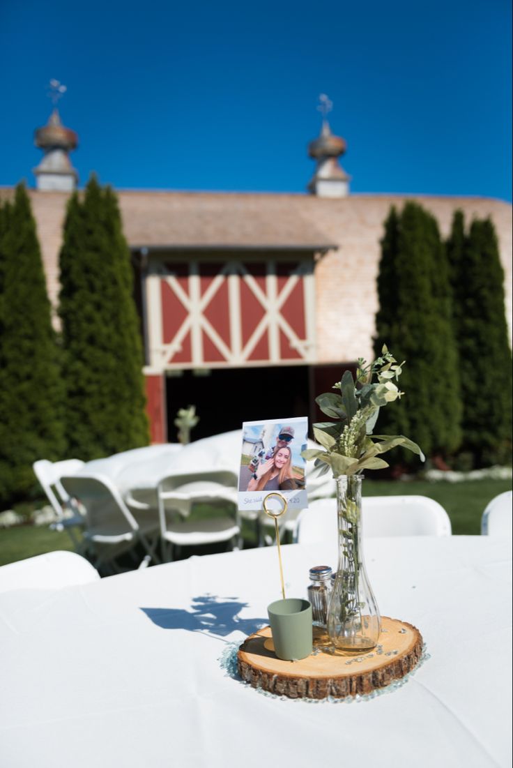 a vase filled with flowers sitting on top of a white table covered in cloths