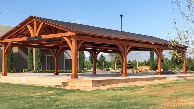 a wooden pavilion sitting on top of a lush green field