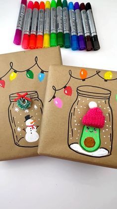 two notebooks decorated with christmas decorations and snowmen are next to crayon markers