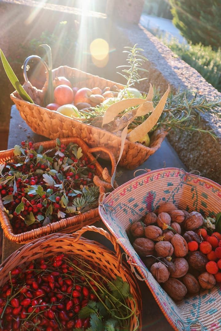 baskets filled with different types of fruits and vegetables on top of a wooden table in the sun