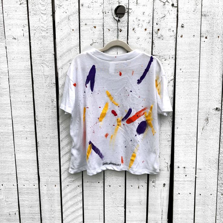 DESCRIPTION The perfect cropped white T shirt. Assorted color splatter and stripes painted on back, with small heart painted on front, upper left side in red. Signed @wrenandglory. Due to each piece being hand painted, each piece might have slight differences. Please allow 1-2 weeks delivery, as each piece is hand painted, and made to order. Limited edition. EACH PIECE IS MADE TO ORDER, HAND PAINTED BY GLORIA AND HER TEAM IN THEIR NYC STUDIO FIT Vintage Jersey - 50% Cotton, 50% Polyester Set-in Hand Painted T Shirts, Hand Painted Shirts, Pride Fits, Paint Shirt, Painted Fashion, Mess Hall, Fabric Paint Shirt, Painting Fabric, Painted Clothing