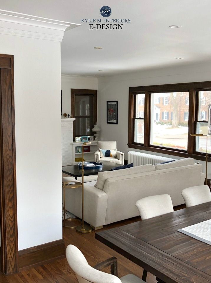 a living room and dining area with wood floors, white furniture and large open windows