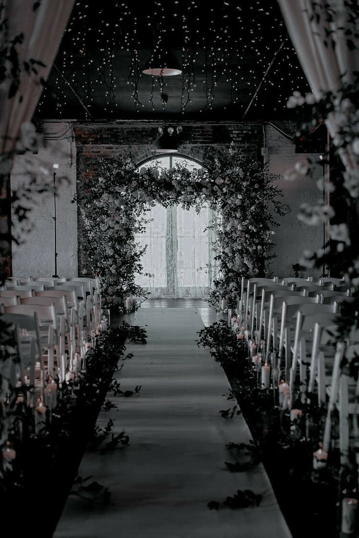 the aisle is decorated with candles and greenery for an outdoor wedding ceremony at night