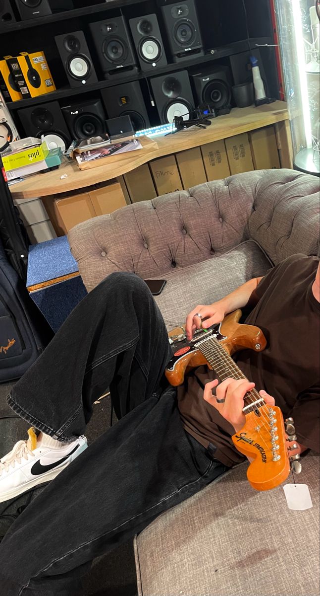 a man laying on top of a couch holding an electric guitar