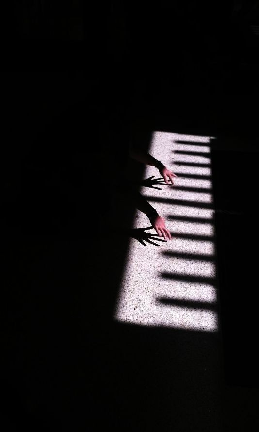 the shadow of a person's hand on a piano keyboard with words written below it