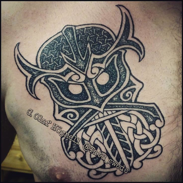 the back of a man's chest with an intricate tattoo design on his left side