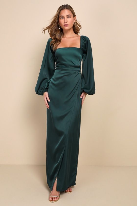 a woman wearing a green dress with long sleeves and an asymmetrical neckline