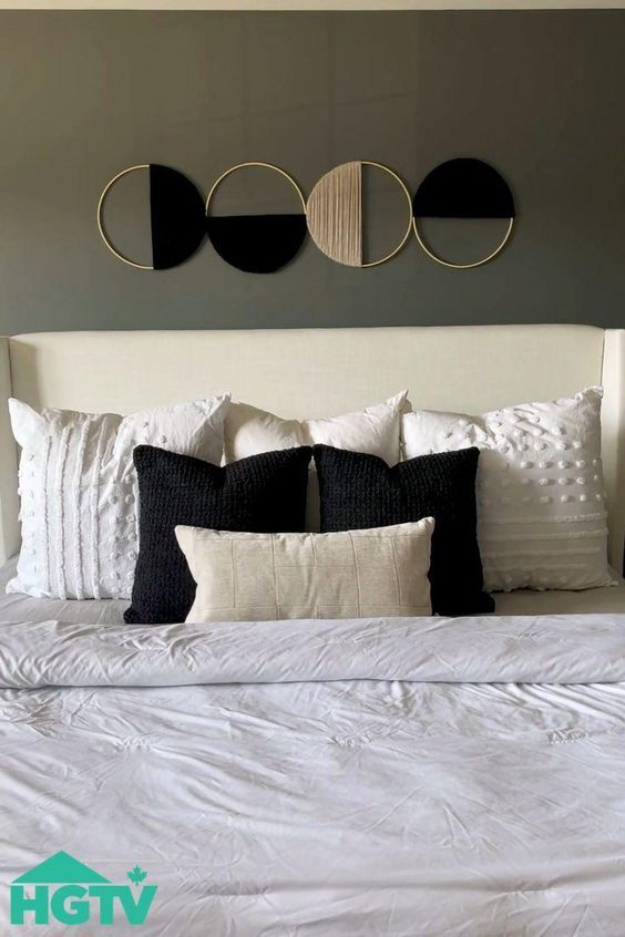 a white bed topped with pillows and two circular mirrors above it's headboard