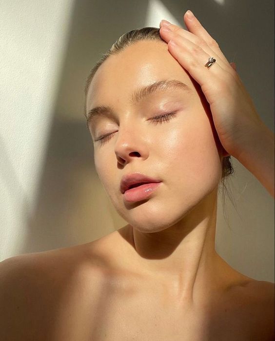 a woman with her eyes closed and hands on her head, posing for the camera