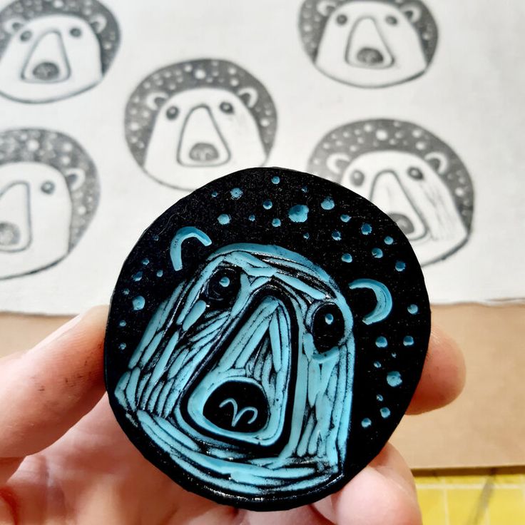 a hand holding up a black and blue button with an image of a bear on it